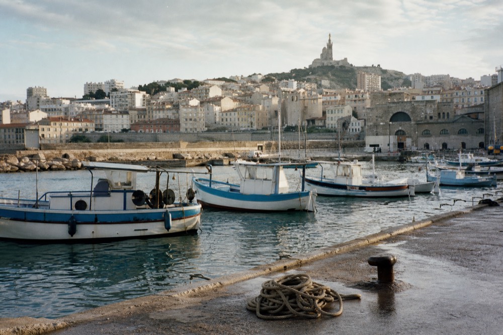 Old port of Marseille with fishing boats and the Notre-Dame de la Garde basilica on the hill, no text, no logos, no people