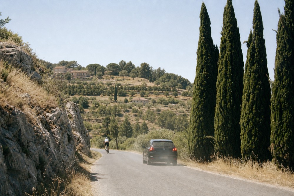 Winding road through Provençal countryside with cypress trees, no text, no logos, no people
