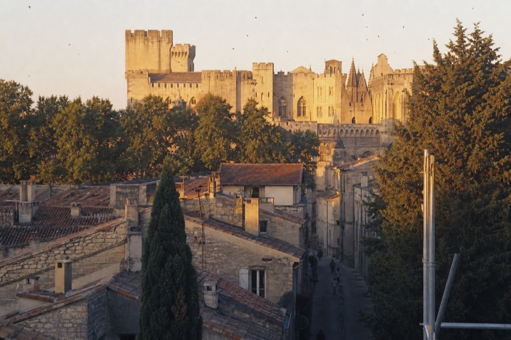 Golden late-afternoon light on the palace walls and rooftops of Avignon, no text, no logos, no people.
