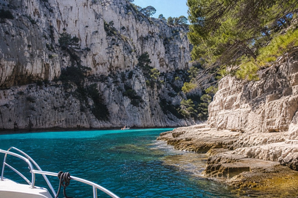 White limestone cliffs of a calanque inlet above turquoise water, no text, no logos, no people