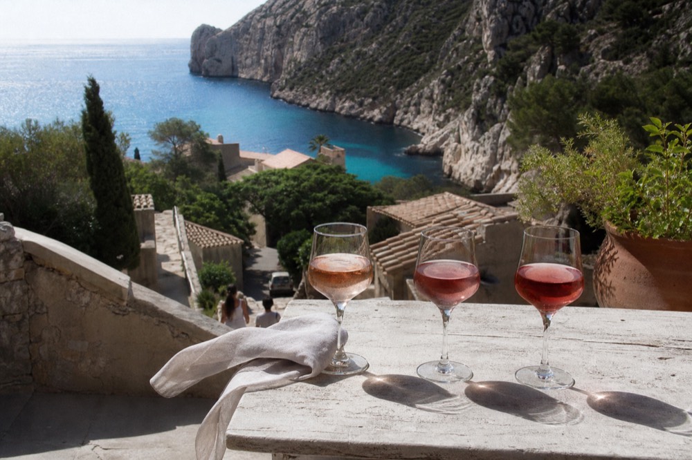 A terrace tasting overlooking the Mediterranean with three glasses of rosé in different shades of pink, no text, no logos, no people