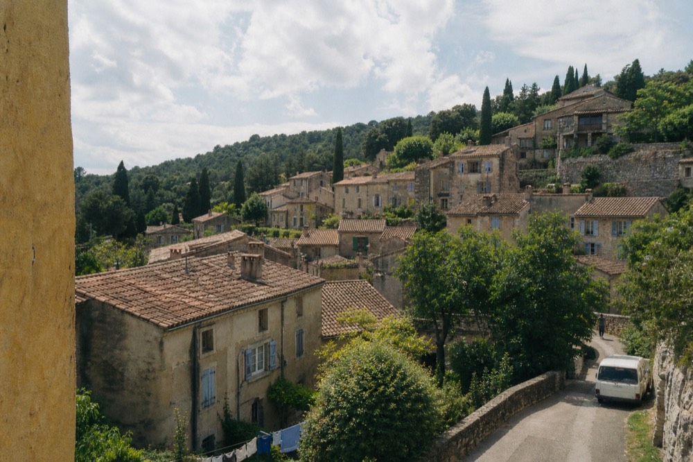 A stone hilltop village with terracotta roofs among cypress trees, no text, no logos, no people