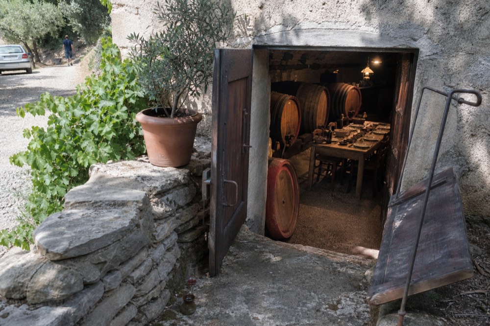A stone cellar door with wooden barrels open for a wine tasting, no text, no logos, no people