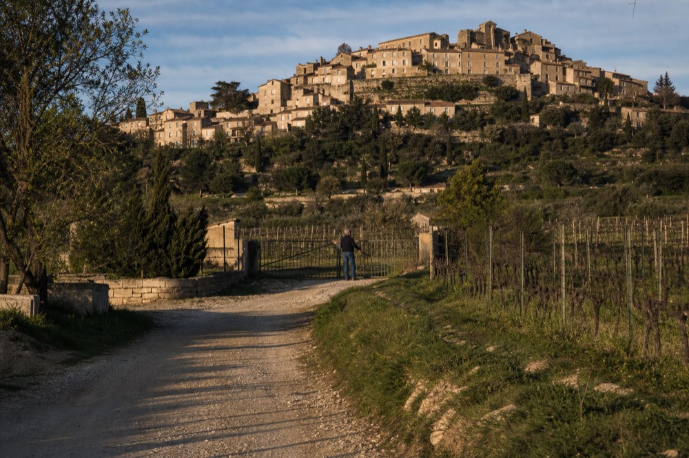 Hilltop village above Luberon vineyards in late afternoon light, no text, no logos, no people